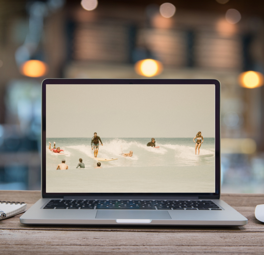 Laptop on a beach bar with surfers on the screen